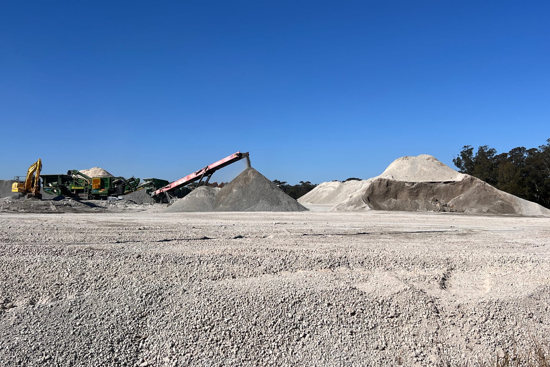 The crushing plant at Glenfield Waste Services, its conveyor building a stockpile of crushed material, with further product piles across the working floor.